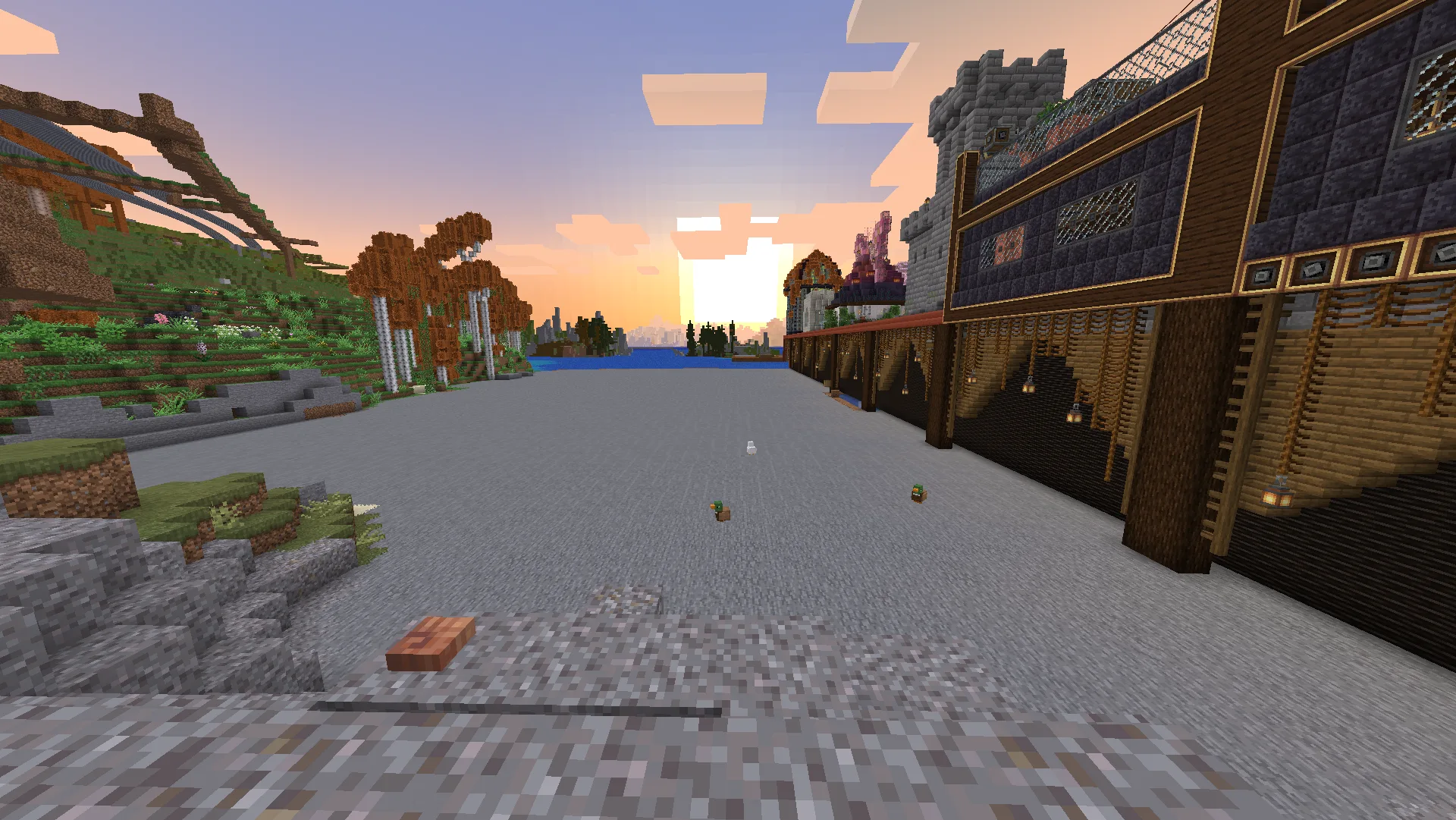 A broad new stone platform at sunset where a lake had been, bordered by large timber-and-stone builds.
