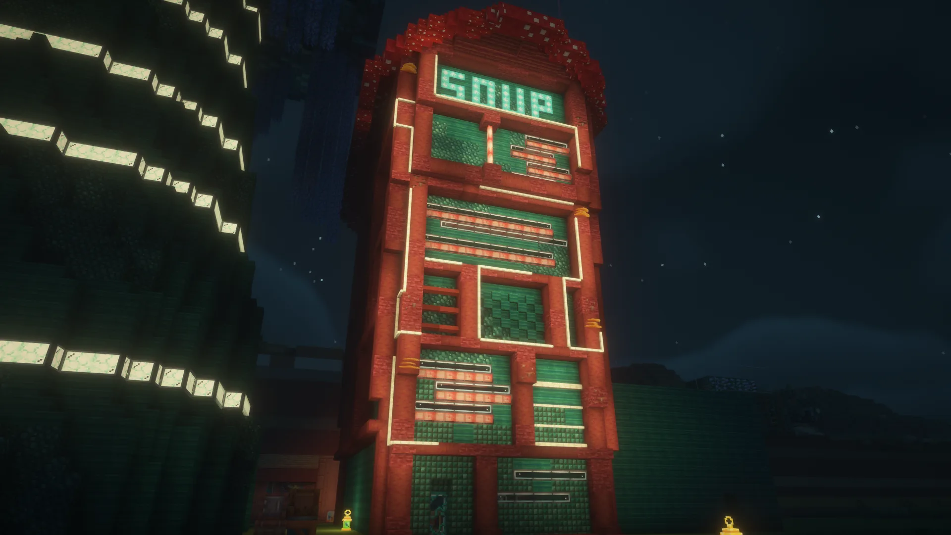 A red-and-green mushroom-city facade glowing at night, with a turquoise SOUP sign above its patterned front.