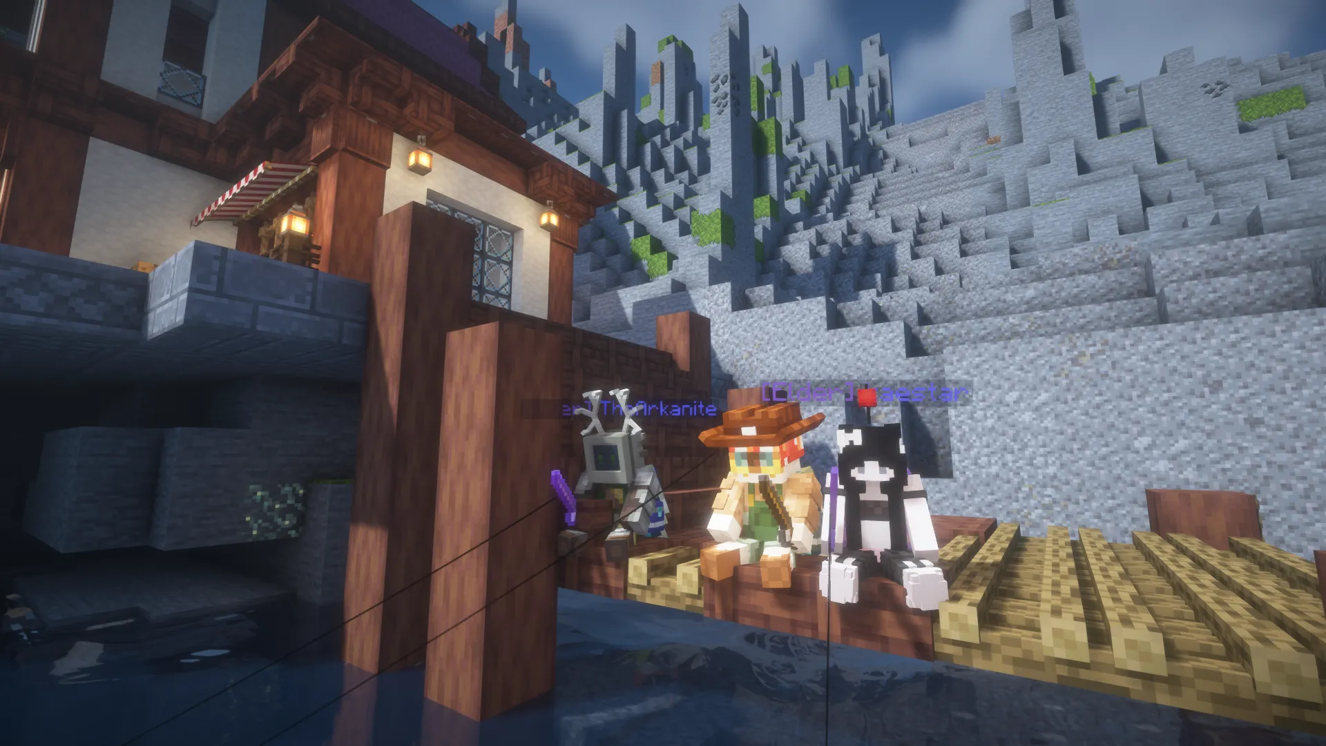 Three players fish from the wooden docks of a lantern-lit Homestead village beneath a steep stone mountainside.