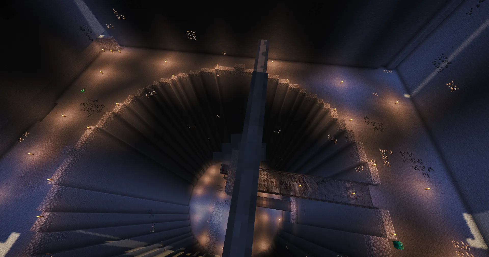 A torch-lit circular excavation viewed from above, crossed by a narrow central shaft and catwalk.