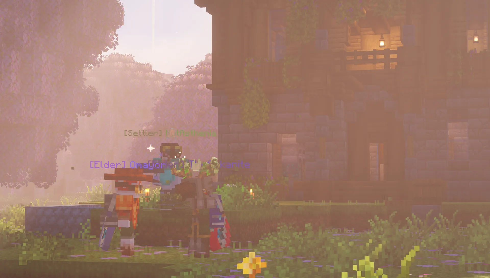 Three players stand together in warm evening light outside a dark stone-and-timber Homestead building.
