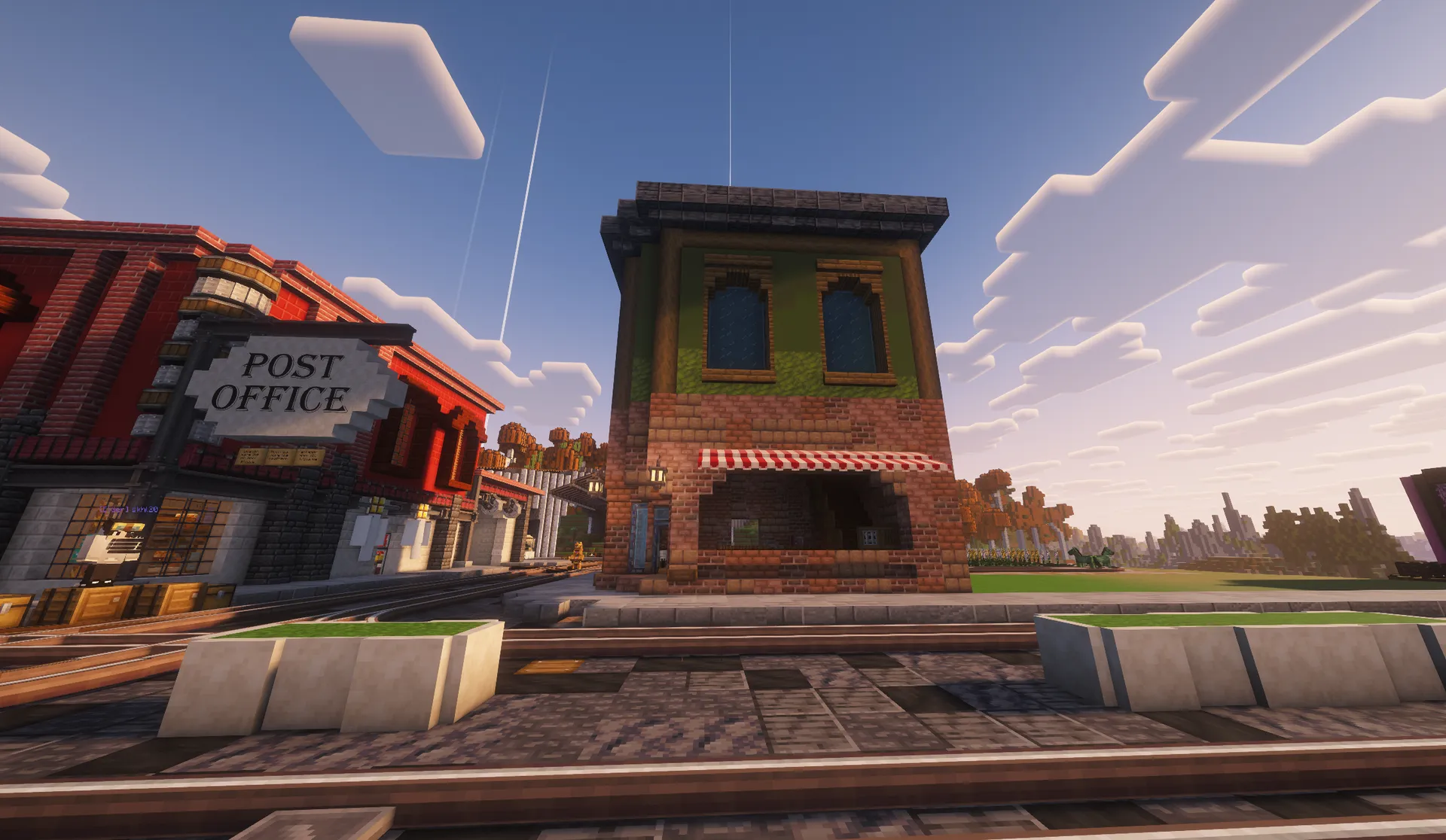 A two-story green-and-brick sandwich shop with a striped awning beside Homestead’s post office and railway tracks.