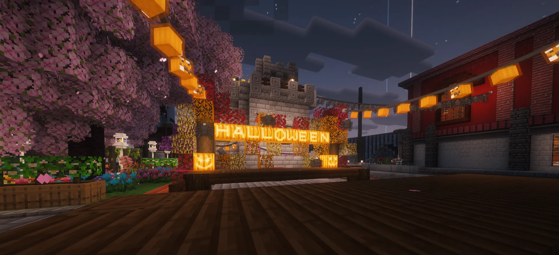A lantern-lit Halloween plaza at night, framed by pink trees, pumpkins, a stone tower, and a red building.