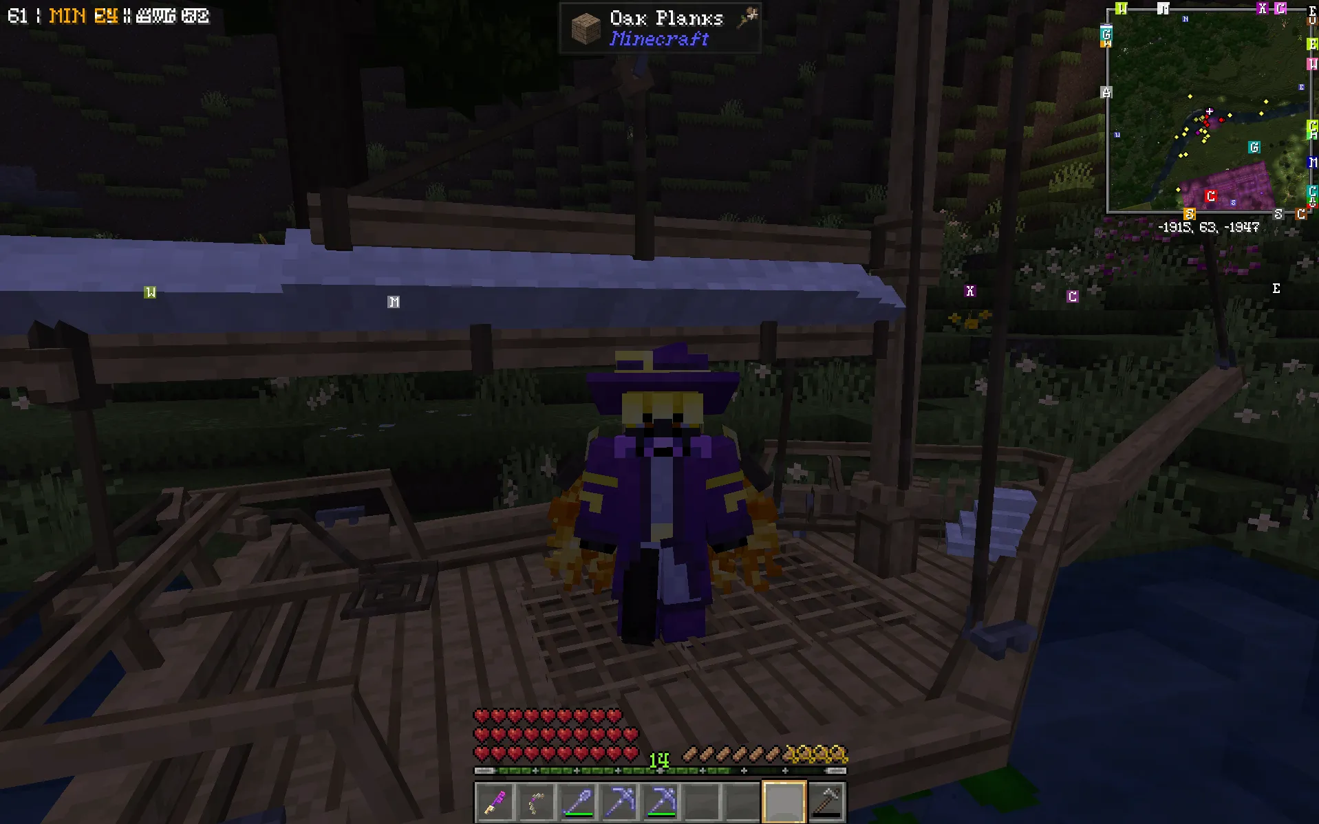 A player in a purple wizard hat and robes stands aboard a wooden sailing boat beside a wooded riverbank at night.